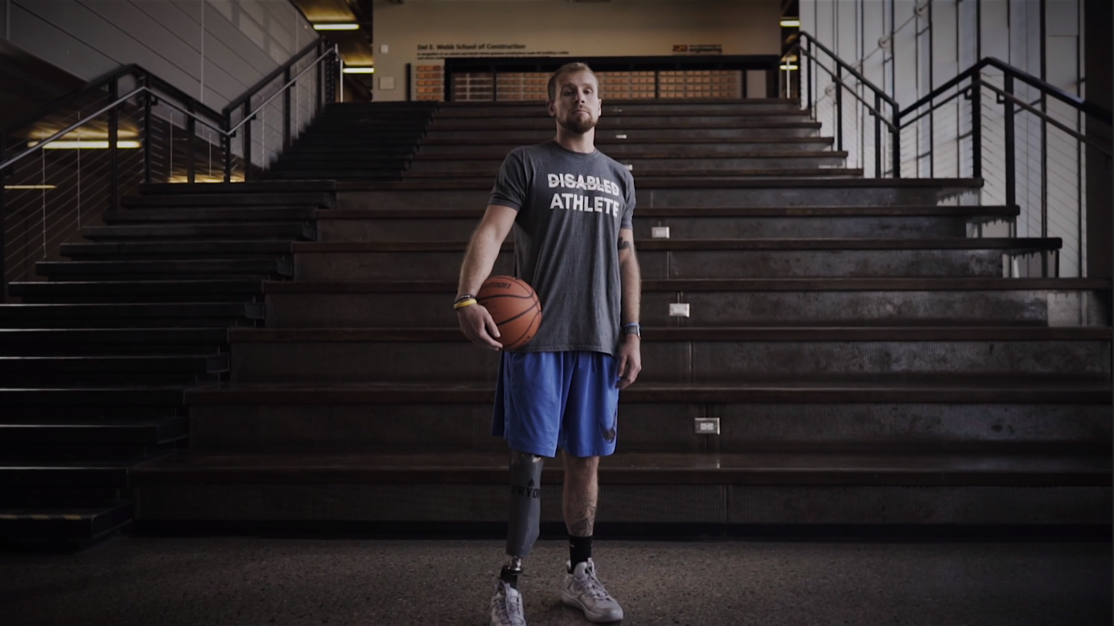Nick Pryor standing with basketball in hand in front of a set of stairs