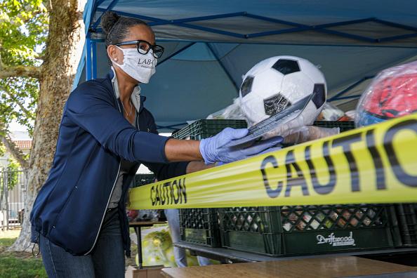 Renata Simril, of LA84, Foundation, distributes sports goods to under-served kids, at LAUSD Grab and Go meal center at Thomas Alva Edison School. Thomas Alva Edison Middle School on Wednesday, May 6, 2020 in Los Angeles, CA. (Irfan Khan / Los Angeles Time