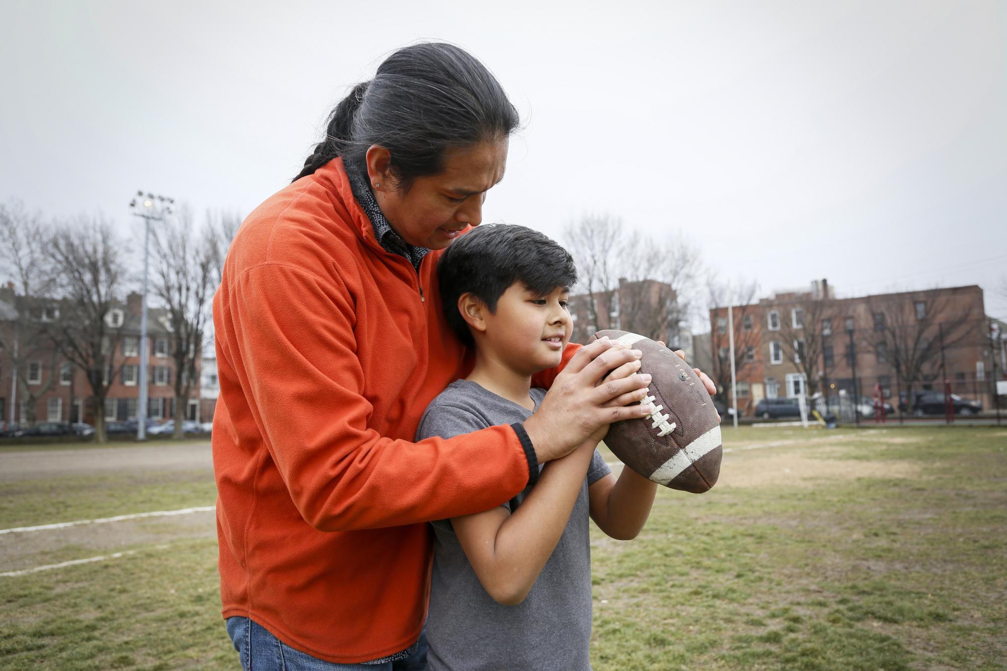 Native American father teaching son to throw football.