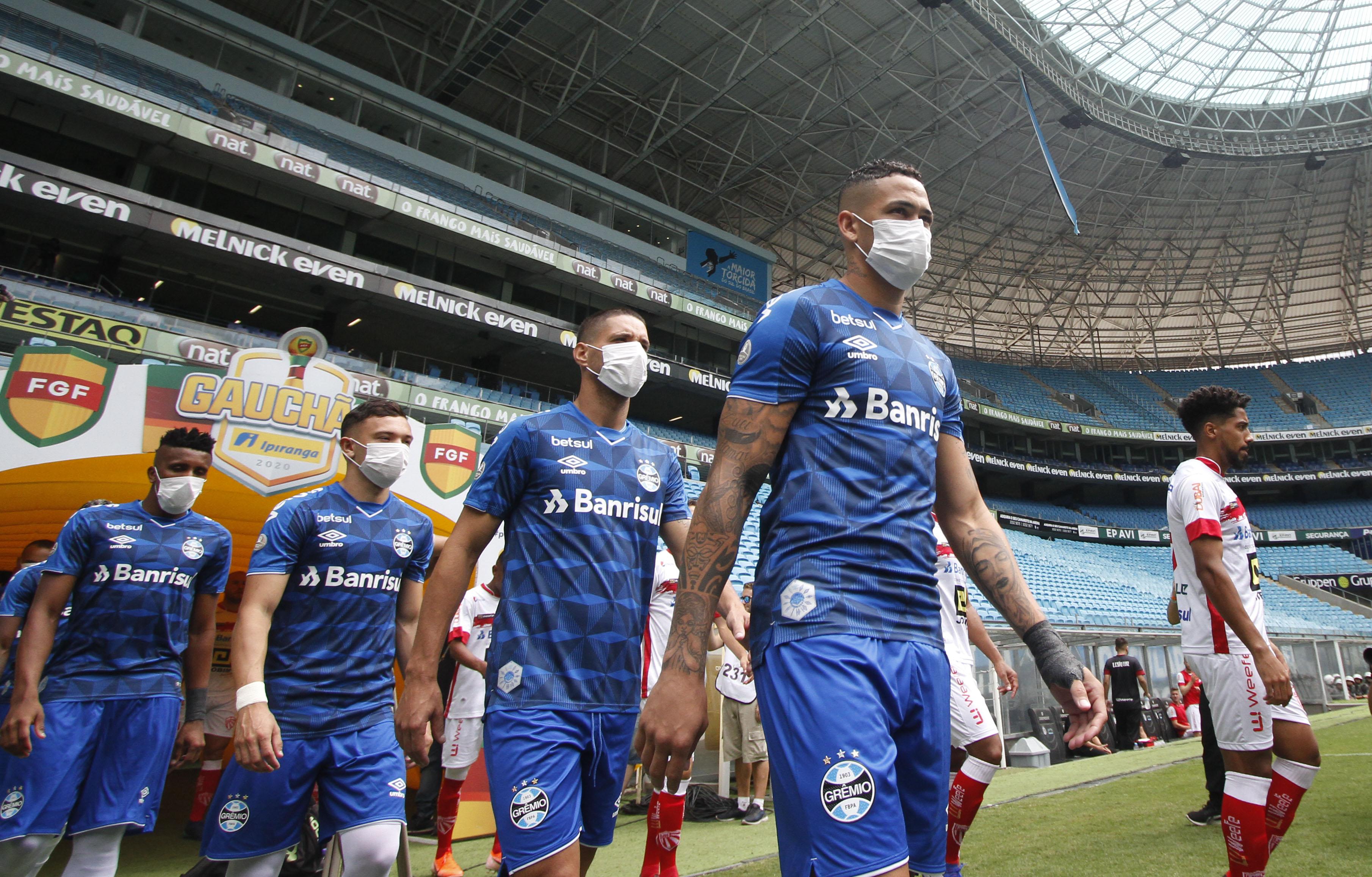 Players of Gremio enter the field wearing protective face masks to prevent the spread of the new Coronavirus, before the match against Sao Luiz, at the closed-doors Arena do Gremio stadium, in Porto Alegre, Brazil, on March 15, 2020.(Photo by Richard DUC)